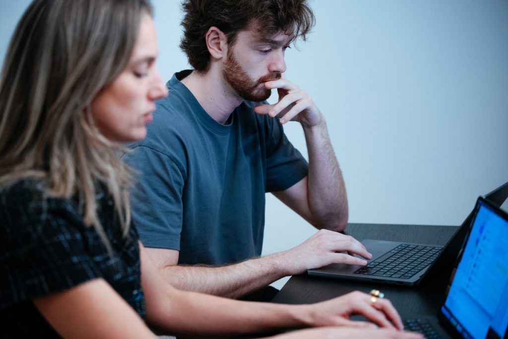 Two people working on laptops together.