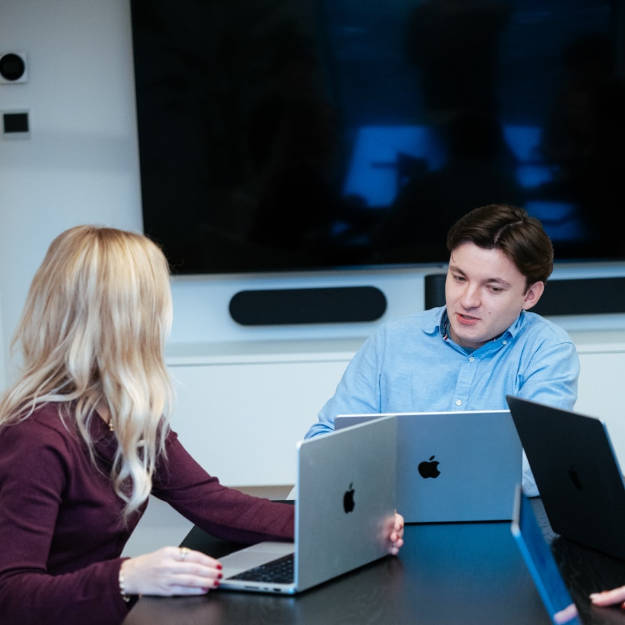 People discussing with laptops in a meeting room.